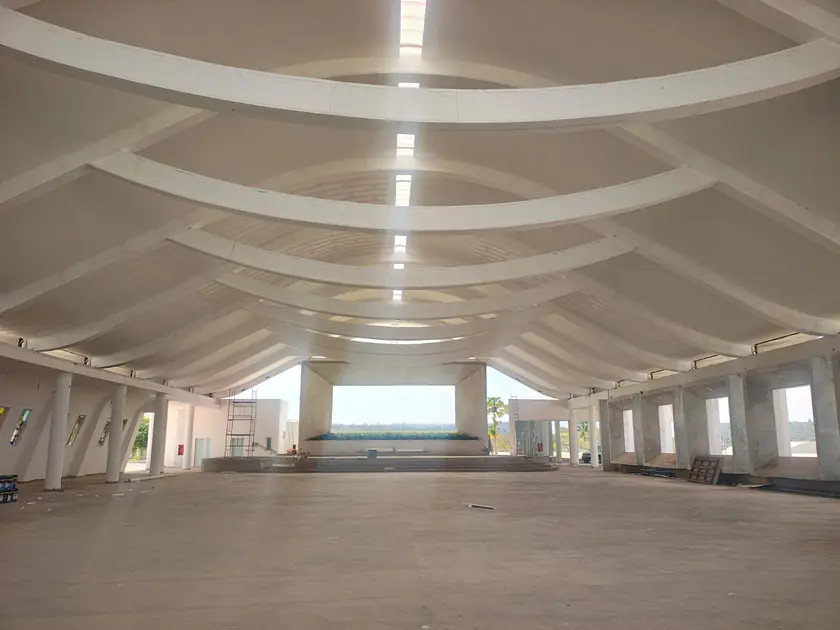 Nave interna com vigas curvas e iluminação linear